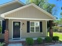 Inviting front porch with brick supports, a black front door with glass, and manicured landscaping at 379 Maiden Sw Ln, Concord, NC 28025