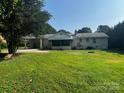 View of the home's back exterior with a screen porch, carport and large yard at 629 Belmorrow Dr, Charlotte, NC 28214