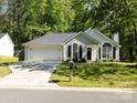 Single-story home with attached garage and landscaped front yard, showcasing its pleasant curb appeal at 7731 Ivy Hollow Dr, Charlotte, NC 28227