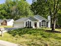 Inviting single-story home with green lawn, mature trees, attached garage, and charming front exterior at 7731 Ivy Hollow Dr, Charlotte, NC 28227
