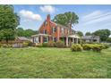 Sprawling red brick home with a manicured lawn and mature trees creating a peaceful setting at 901 Central Dr, Kannapolis, NC 28083