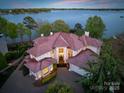 Expansive lakefront home features a red tile roof, manicured landscaping, and a circular driveway at 102 Eastham Ct, Mooresville, NC 28117