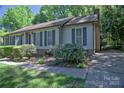 Well-maintained home exterior with neat landscaping, gray siding, dark shutters, and a brick chimney, offering cozy charm at 10708 Danesway Ln, Cornelius, NC 28031
