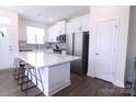 Modern kitchen with white cabinets, stainless steel appliances, a center island with seating, and hardwood floors at 1075 South Point Rd, Belmont, NC 28012
