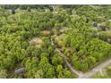 Aerial view of a secluded wooded property with a long driveway and various buildings, backing to a rural road at 124 Neumann Run, Belmont, NC 28012