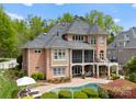 A brick home featuring an outdoor pool, patio, screened porch and mature trees at 13420 Robert Walker Dr, Davidson, NC 28036