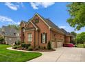 A brick house boasts a three-car garage and manicured landscaping in a circular driveway at 13420 Robert Walker Dr, Davidson, NC 28036