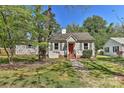 Quaint one-story home featuring a red front door, gray siding and mature trees at 1944 Garibaldi Ave, Charlotte, NC 28208