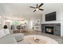 Open-concept living space with stone fireplace, modern ceiling fan and view of a spacious kitchen and dining area at 5162 Beckenham Ln, Concord, NC 28025