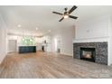 Open-concept living room featuring a stone fireplace, hardwood floors, and a modern ceiling fan at 5162 Beckenham Ln, Concord, NC 28025