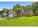 Attractive brick home with a lush front lawn and mature trees on a sunny day at 6002 Sentinel Dr, Indian Trail, NC 28079