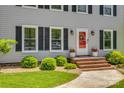 Home's entrance boasts brick steps, manicured shrubs, and classic shutters framing bright windows at 7300 Chatterbird Ct, Charlotte, NC 28226