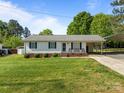 Charming single-story home featuring manicured lawn, carport, and inviting front porch with cozy bench seating at 1238 Moss Springs Rd, Albemarle, NC 28001