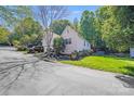 A suburban home featuring an attached garage, landscaped yard, and mature trees at 13817 Kings Carriage Ln, Charlotte, NC 28278