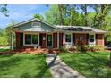 Inviting brick home featuring a walkway leading to the front door and well maintained lawn at 1501 Briarfield Dr, Charlotte, NC 28205