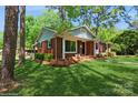 Cozy brick house with a manicured lawn, complete with a charming front porch and an American flag at 1501 Briarfield Dr, Charlotte, NC 28205