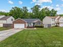 Inviting single-story home with brick details, an open front yard, an attached two-car garage, and a quaint deck at 3022 Willamette Valley Dr, Charlotte, NC 28215