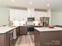 Modern kitchen with white cabinetry, stainless steel appliances, island with quartz countertops, and hardwood floors at 417 Tristram Ln, Charlotte, NC 28205