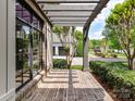 Covered brick patio featuring an open pergola, black frame windows, and lush greenery at 825 Hudson Pl, Davidson, NC 28036