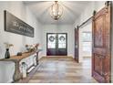 Elegant foyer with hardwood floors, statement lighting, and a decorative console table near a sliding barn door at 1336 W Rebound Rd, Indian Land, SC 29720
