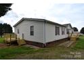 The rear exterior features a side door, a wooden deck and brick foundation at 234 Olin Loop, Olin, NC 28660