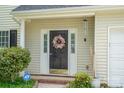 Home's front door with a wreath and matching sidelights, windchimes, and tidy landscaping at 407 Goodloe Dr, Charlotte, NC 28262