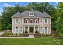 Stately stone and brick home with manicured landscaping and lush green lawn at 7005 Camrose Crossing Ln, Matthews, NC 28104
