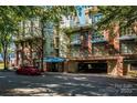 Exterior shot of multi-story condo building with brick facade, balconies, and covered parking, all beneath mature shade trees at 1101 W 1St St # 405, Charlotte, NC 28202