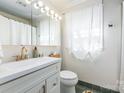 Bright bathroom features white vanity with gold faucet, modern lighting, and stylish green tile flooring at 1114 Hartford Ave, Charlotte, NC 28209