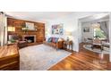 Cozy living room with wood-paneled accent wall, brick fireplace, hardwood floors, and neutral area rug at 1114 Hartford Ave, Charlotte, NC 28209