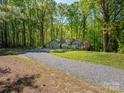 Wide shot of the home's exterior showcasing its setting amidst a lush, wooded landscape and long driveway at 211 W Tennessee Ave, Bessemer City, NC 28016