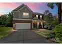 Inviting two-story home with a brick and siding exterior, front porch with rocking chairs, and a well-manicured lawn at dusk at 21907 Torrence Chapel Rd, Cornelius, NC 28031