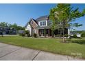 Inviting two-story home featuring a covered porch, well-manicured lawn, and mature landscaping at 2380 Fairport Se Dr, Concord, NC 28025