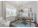 Bright home office features a modern chandelier, large window, and built in cabinetry with a decorative rug at 3619 Slider Ter, Lancaster, SC 29720