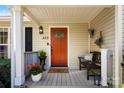 Cozy front porch featuring a bright orange door, decorative accents, bench, and fresh greenery at 459 Cramerton Rd, Gastonia, NC 28056