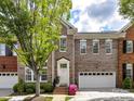 Charming brick townhome featuring manicured landscaping, attached garage, and inviting front entrance with colorful flowers at 6133 Wakehurst Rd, Charlotte, NC 28226
