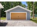 A detached gray garage featuring a double wide door, perfect for storage or a workshop, sits on a concrete pad at 7141 Pitchfork Ln, Mint Hill, NC 28227