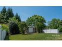 Backyard with a shed, green grass, bushes, trees, and a white fence at 1004 Toquima Trl, Monroe, NC 28110