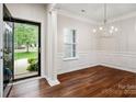 Elegant dining room featuring hardwood floors, wainscoting, a modern chandelier, and abundant natural light at 1004 Toquima Trl, Monroe, NC 28110