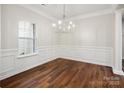 Bright dining room with beautiful hardwood floors, wainscoting detail, and a modern chandelier at 1004 Toquima Trl, Monroe, NC 28110