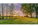 Sunset view over green property with mature trees and outbuildings at 153 Coachman Loop, Statesville, NC 28625