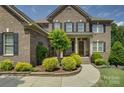 Elegant brick home with lush landscaping, a covered porch, and a stylish front door at 16519 Flintrock Falls Ln, Charlotte, NC 28278