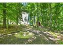Secluded backyard features a stone fire pit, surrounded by mature trees and lush greenery at 2417 Labelle Dr, Waxhaw, NC 28173
