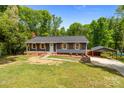 Charming single-story home with gray siding, wood shutters, and a covered carport in the driveway at 4050 Leafmore St, Concord, NC 28027
