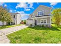 Inviting two-story house with a cozy porch and driveway surrounded by lush green grass and blue skies at 6418 Castlewynd Ct, Charlotte, NC 28212