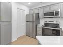 Updated kitchen features stainless steel appliances, gray cabinets with gold pulls, and wood flooring at 6523 Clavell Ln, Charlotte, NC 28210