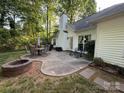 Spacious backyard featuring a patio with outdoor dining set, fire pit, and well-maintained lawn at 8623 Cedar Hollow Ln, Huntersville, NC 28078
