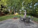 Backyard view showing patio, dining set, and lush trees providing privacy and shade at 8623 Cedar Hollow Ln, Huntersville, NC 28078