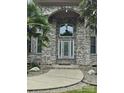 Close up of the front entrance featuring a leaded glass door framed by a brick archway and manicured landscaping at 9535 Potter Rd, Matthews, NC 28104