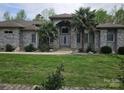 Elegant one-story home featuring a brick facade, well-maintained lawn, and mature palm trees at 9535 Potter Rd, Matthews, NC 28104